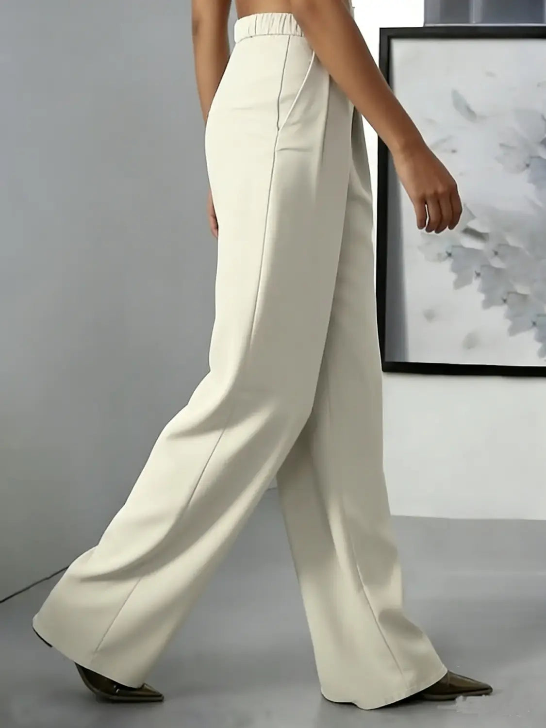 Pantalons à jambes larges couleur crème avec une taille haute, un design plissé, une coupe sur mesure et des détails de coutures latérales discrets.