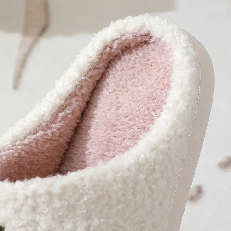 white plush jack-o-lantern embroidered halloween slipper with a soft pink interior lining and fuzzy exterior.