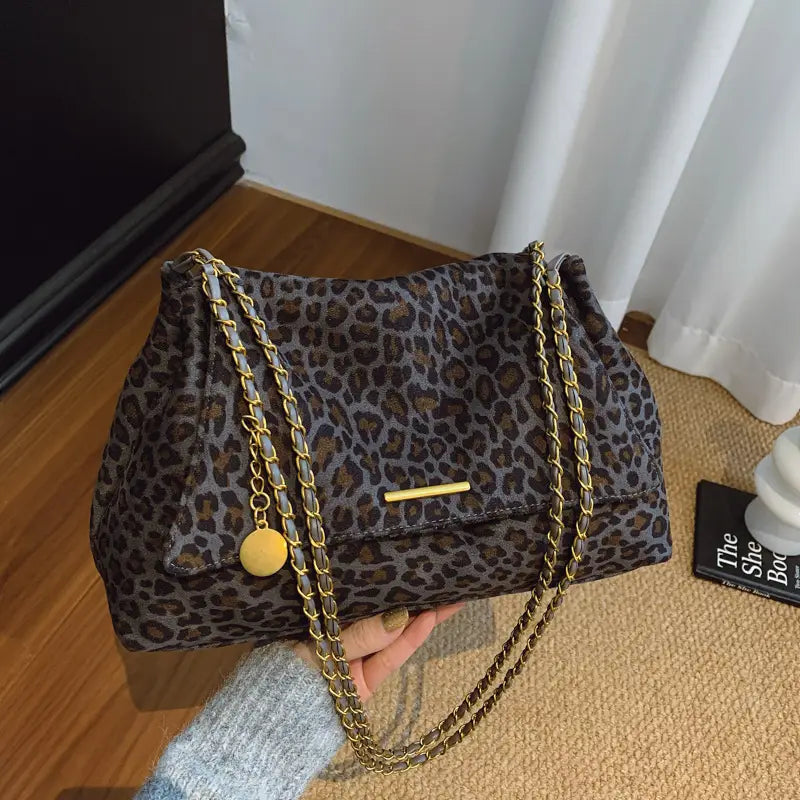 Leopard print crossbody bag with gold-tone chain straps and matching circular charm in a leopard print pattern.