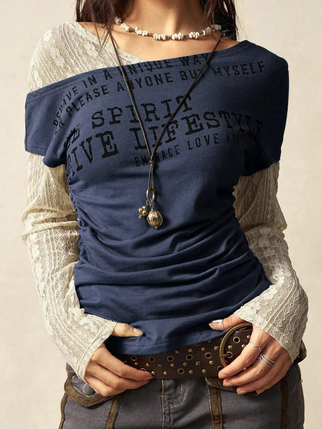 Navy blue off-the-shoulder knitted t-shirt with black printed text layered over a cream lace long-sleeve top in a lace layer off shoulder knitted top design.