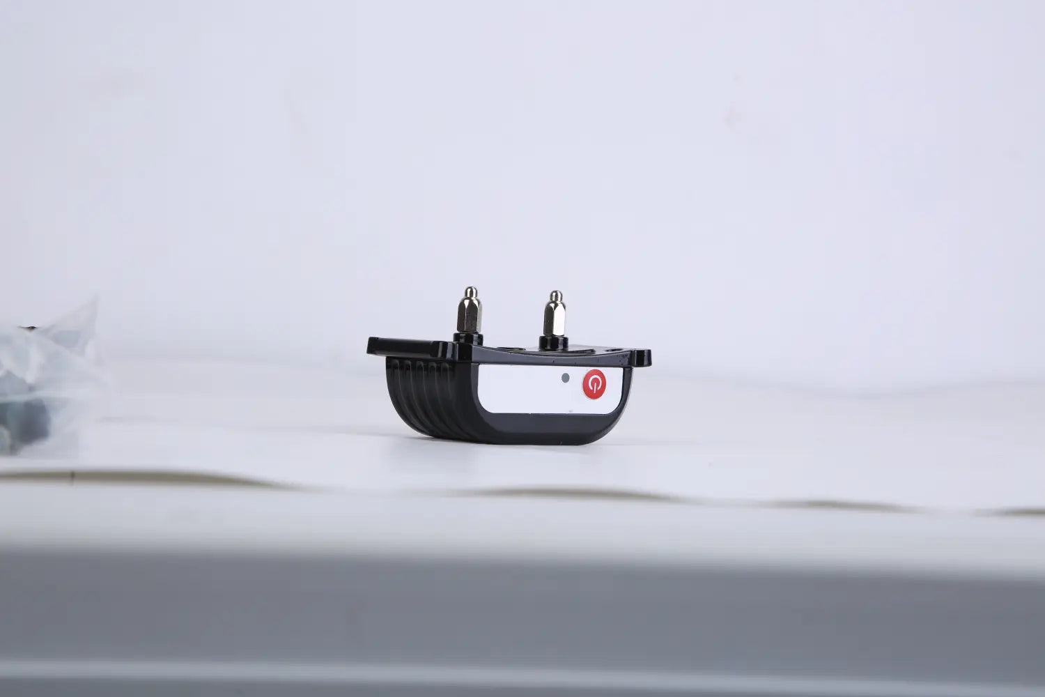 Black plastic 2-in-1 wireless dog fence and remote training collar with two metallic prongs and a red power button on a white label.
