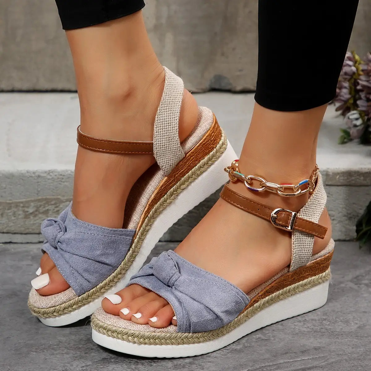 Light blue denim bow wedge sandals with woven rope sole and brown leather buckle ankle straps.
