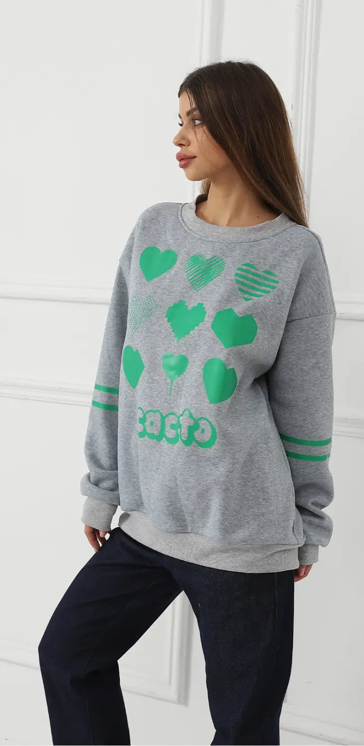 Gray oversized sweatshirt made of soft fabric featuring green heart graphics and the word cacto printed across the chest with two horizontal stripes on each sleeve.