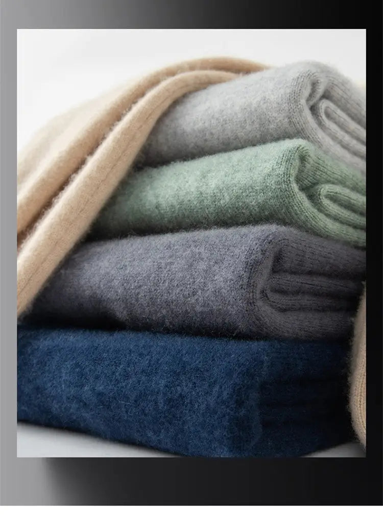 eine gestapelte Auswahl weicher, samtiger Kaschmirschals in neutralen Tönen, darunter Beige, Grau, Salbeigrün und Marineblau, neben einem Herren-Einfarb-Strickpullover im Slim Fit ausgestellt