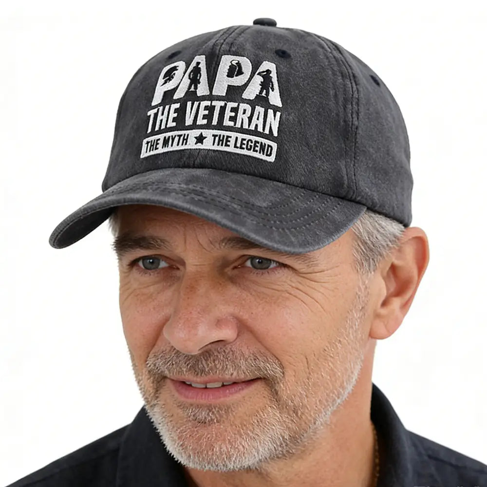 une casquette de baseball en coton gris foncé délavé, brodée d’un texte blanc indiquant « papa le vétéran, le mythe, la légende », et comportant de petites silhouettes de soldats au-dessus de papa ; conçue comme accessoire pour les papas vétérans.