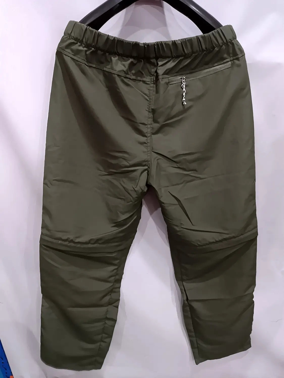 olive green nylon convertible tactical hiking pants with elastic waistband and zippered pocket displayed from the back side