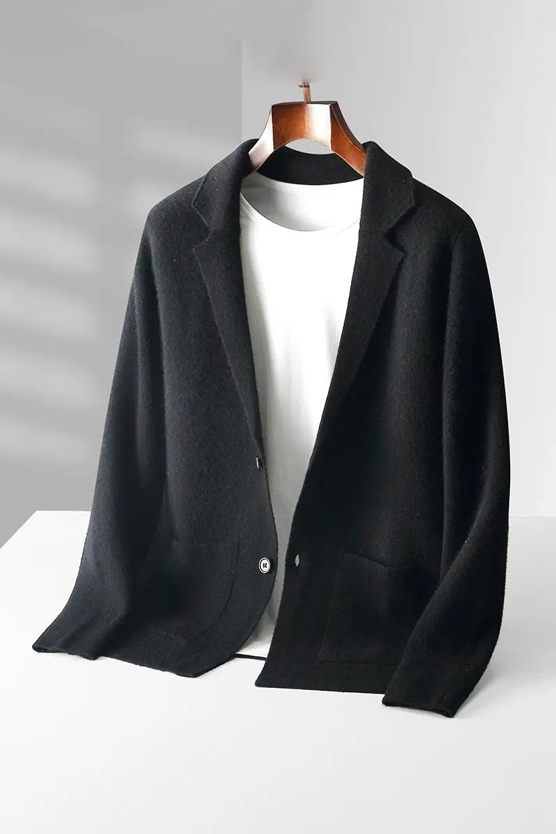Herren V-Ausschnitt-Strickjacke aus olivgrünem Cardigan-Blazer, kombiniert mit einem schwarzen Wollblazer mit Revers mit Kerbe und silbernen Knöpfen, dargestellt auf einem Holzaufhänger über einem weißen T-Shirt