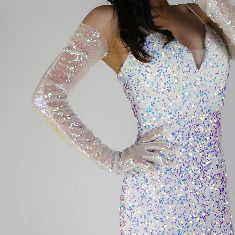 A shimmering white and iridescent sequined evening gown with a plunging neckline and long sheer sleeves paired with matching glittery sequined mesh finger gloves set.