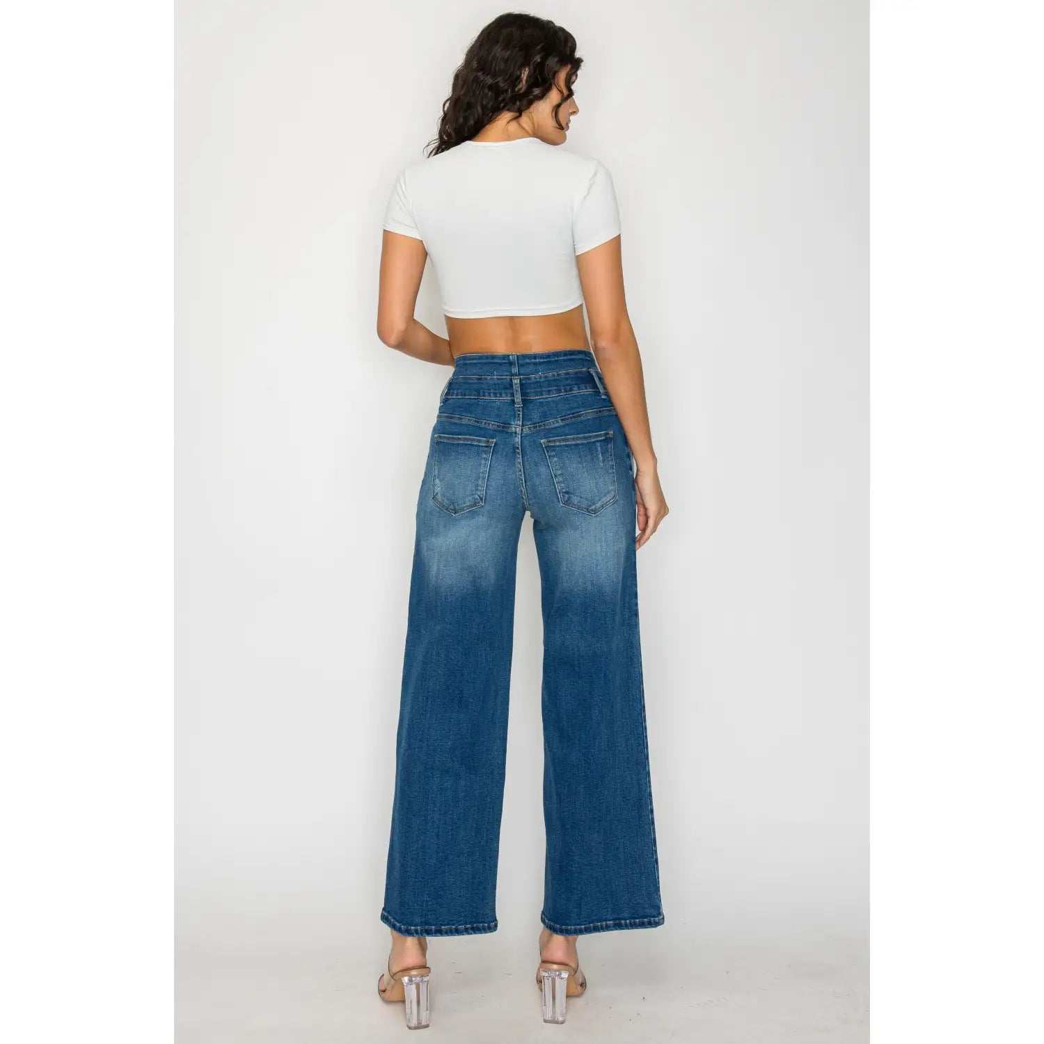 The back side of medium blue wide leg denim jeans features high-waisted blue denim with a wide-leg cut and classic back pockets.