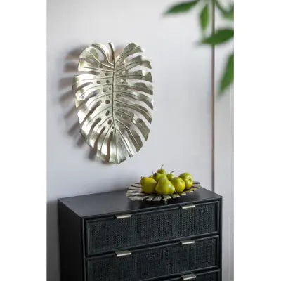 Silver metallic monstera leaf wall art displayed as part of gold monstera leaf wall decor and serving tray collection.