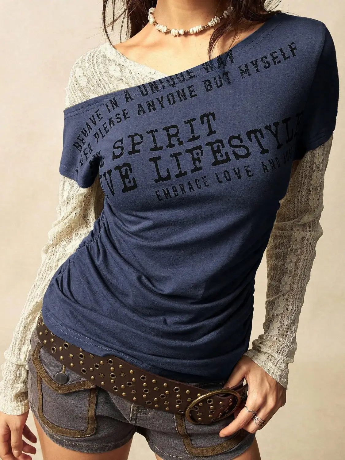 Navy blue short-sleeved knitted top with black printed text and lace overlay sleeve designed as a lace layer off shoulder style.