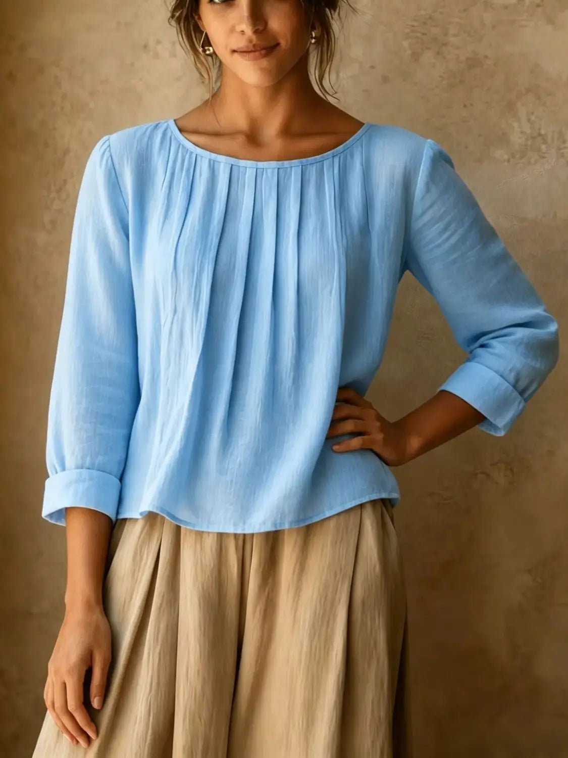 Une blouse ample en lin et coton pour femmes, bleu clair, avec de doux plis, des manches trois-quarts et des poignets retroussés.