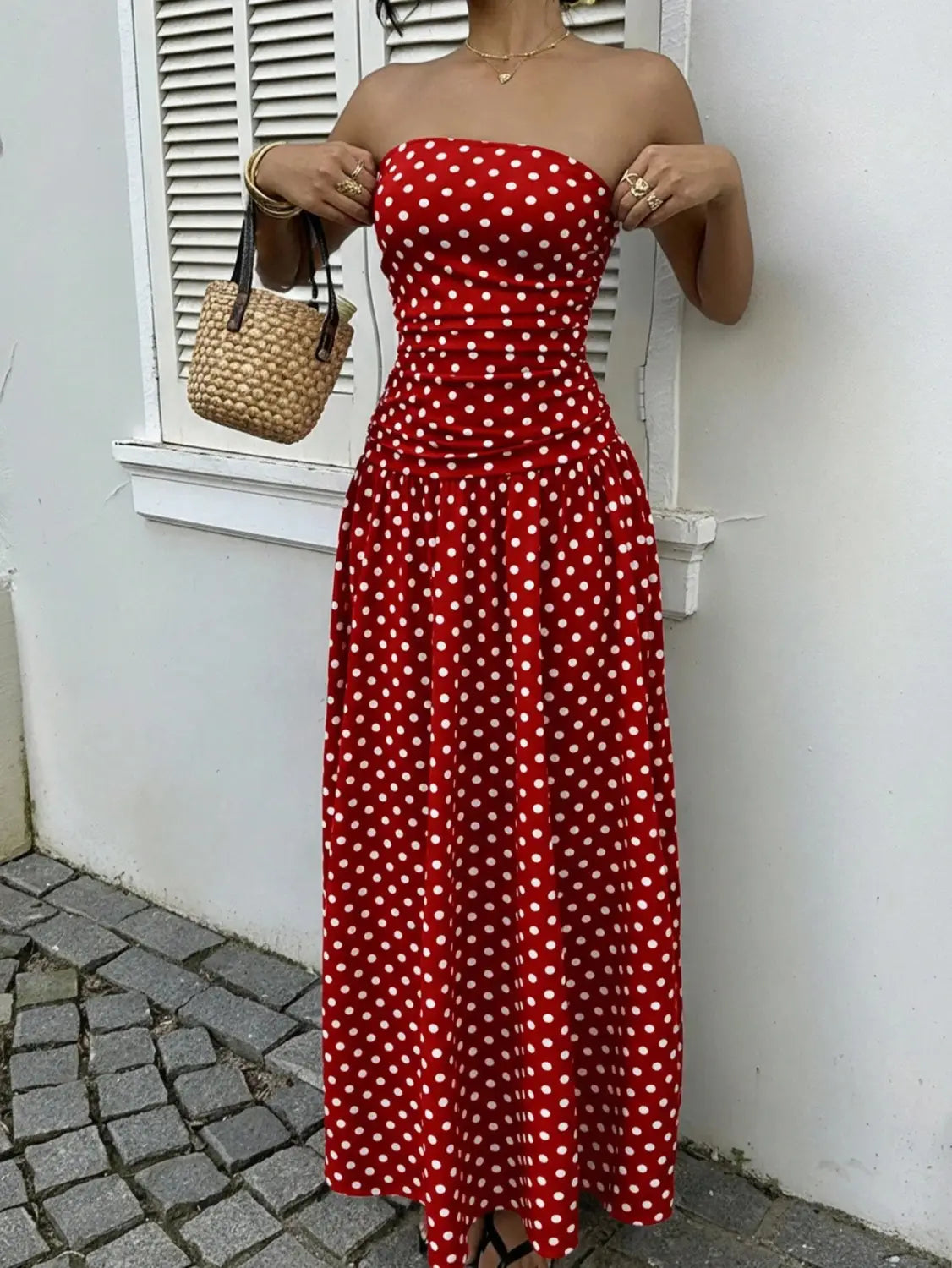 Red strapless maxi dress with white polka dots featuring an off shoulder design perfect for elegant occasions.
