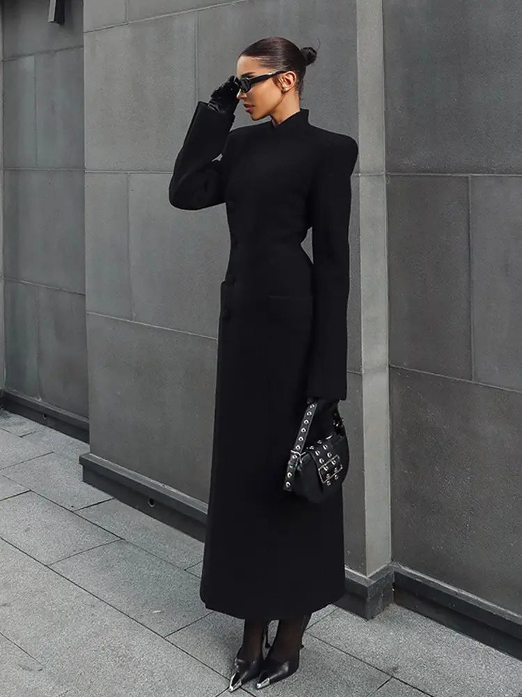 Black studded handbag with a structured minimalist design and metallic hardware accents complementing a charcoal gray wool coat for women waisted long outerwear.