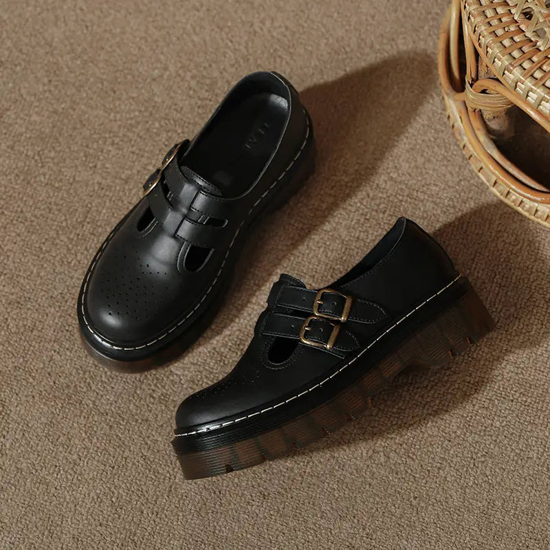 Schwarze Lederschnürstiefeletten auf Plattform im Brogue-Mary-Jane-Stil mit doppelten Messing-Schnallen und perforierten Details am Vorderkappenbereich.