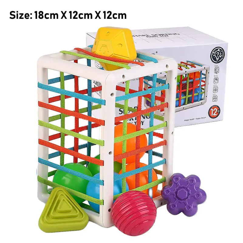 Jouet trieur de formes Montessori pour jeux sensoriels de bébé, comprenant un cadre en plastique blanc avec des bandes élastiques de couleur arc-en-ciel et des blocs géométriques vifs assortis.