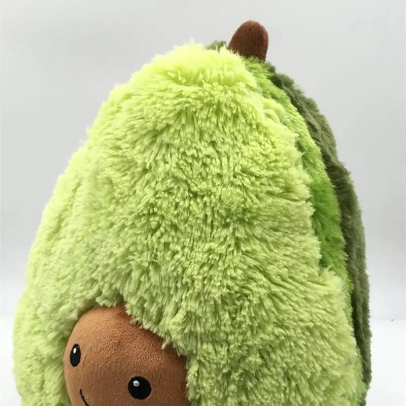A plush avocado toy with a soft fuzzy light green body and darker green skin texture designed as a cartoon pillow.