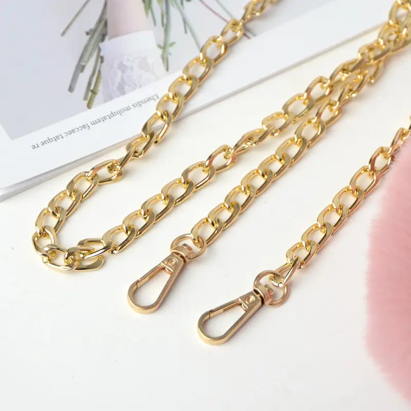 Gold-toned chunky curb chain strap with matching lobster clasps for plush faux fur heart shaped crossbody bag with gold chain.