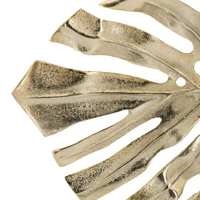 Metallic gold monstera leaf wall decor with a textured sculpted surface and natural vein patterns featured as a decorative piece and serving tray.