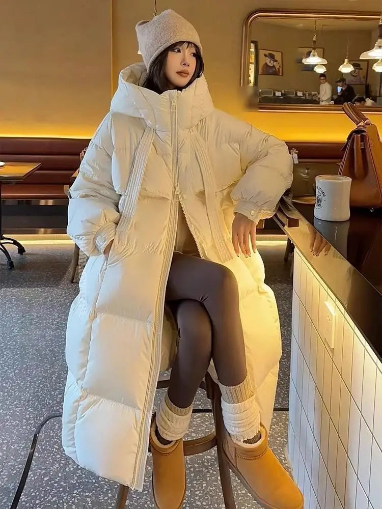 Women long hooded puffer coat in cream color featuring ribbed side panels and a long insulated design.