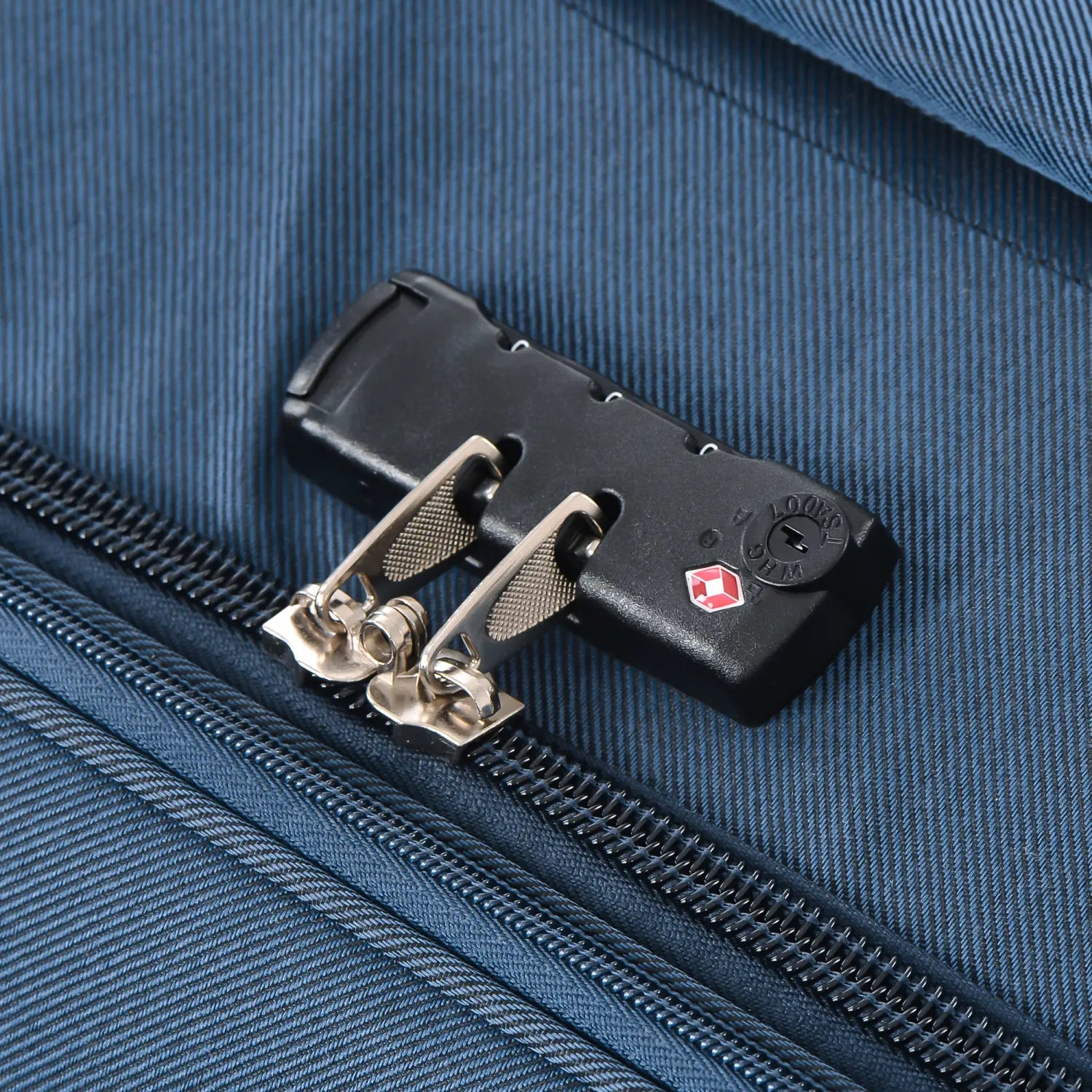 black plastic combination lock with silver metal sliders featuring a red diamond logo and engraved lok branding on navy blue softside expandable 3 piece spinner luggage set
