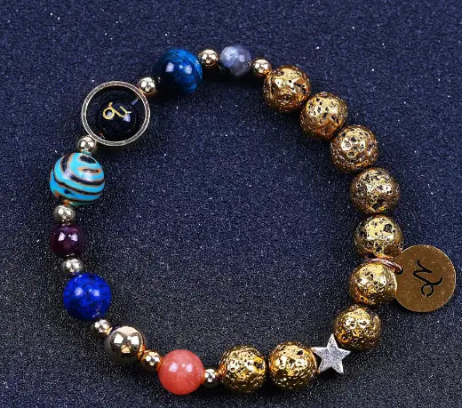 Zodiac volcanic stone beaded bracelet featuring gold-toned lava stone beads with blue and purple gemstones turquoise striped bead orange coral bead silver star charm and zodiac-themed metal charms.