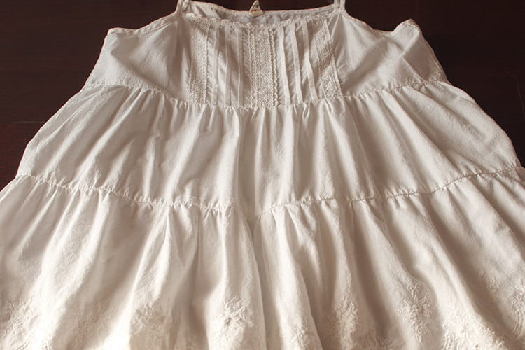Weißes Spitzenkleid mit Volants (gestufter Rock) mit zartem weißem Baumwollstoff, dezenter Stickerei und gestuften Rüschen.