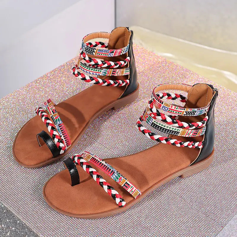 Black and tan strappy flat sandals with colorful braided fabric ankle straps featuring bohemian ethnic patterns.