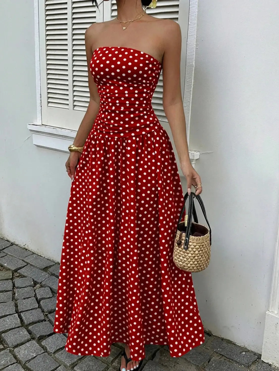Red strapless maxi dress with white polka dots featuring an off shoulder design made from lightweight fabric for elegant occasions.