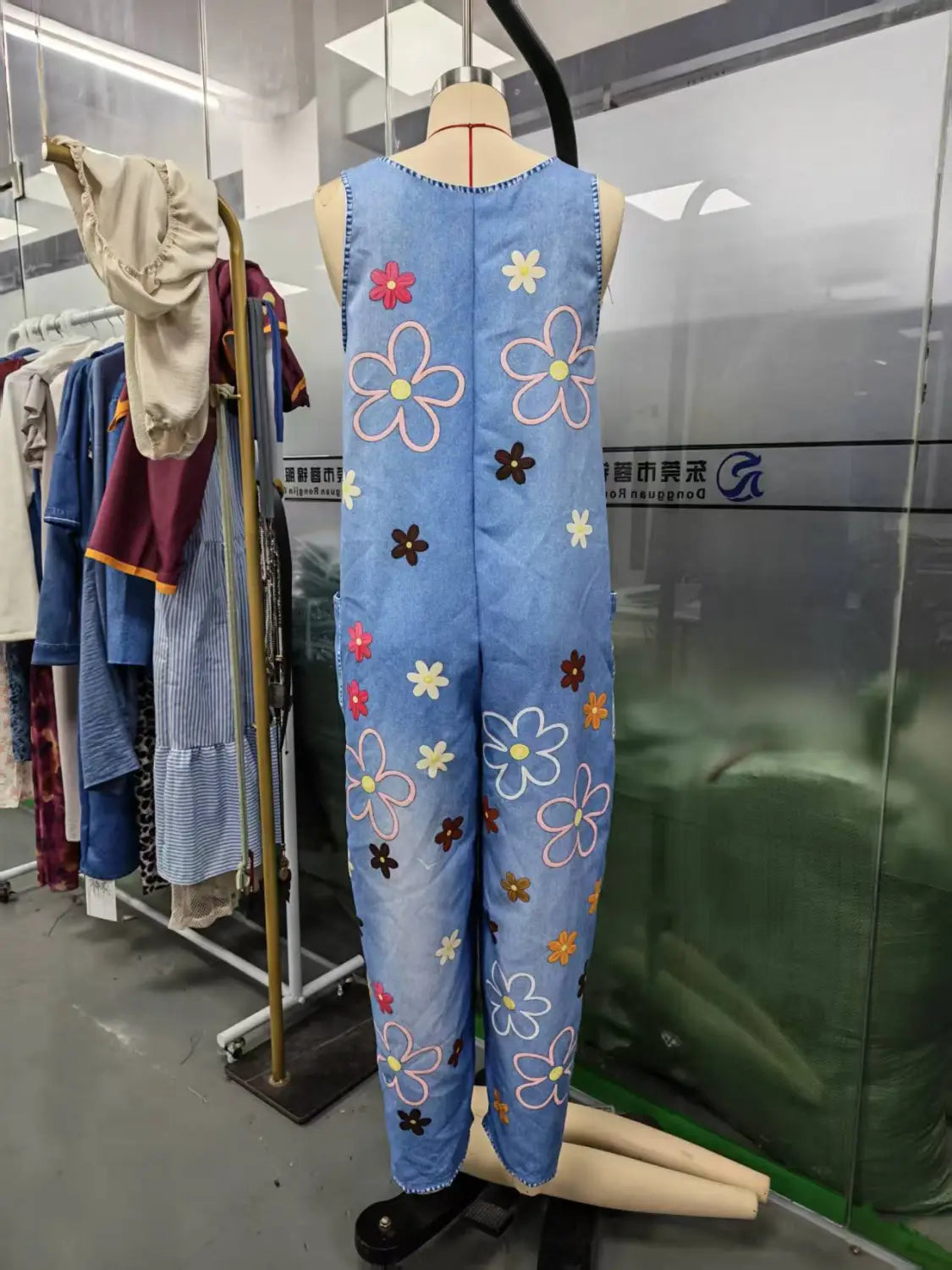 ライトブルーデニムの刺繍入りオーバーオール（ワイドレッグ・レトロパンツ）。カラフルなピンク・白・ブラウンのフローラルデザインを施しています。