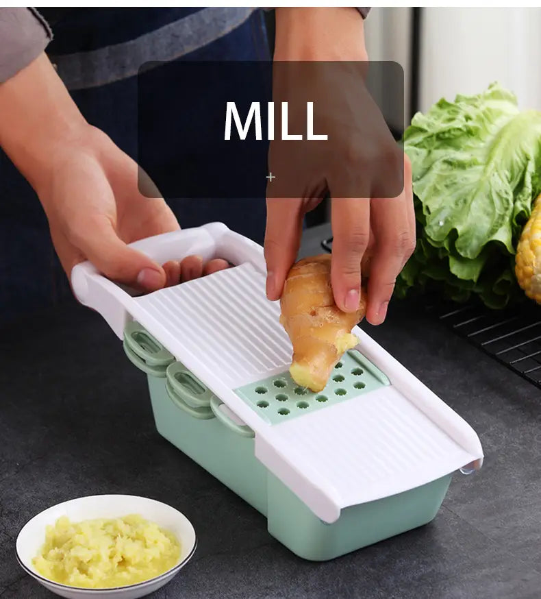 A mint green and white plastic vegetable slicer mandoline grater with a ridged blade designed for slicing or grating root vegetables like ginger.