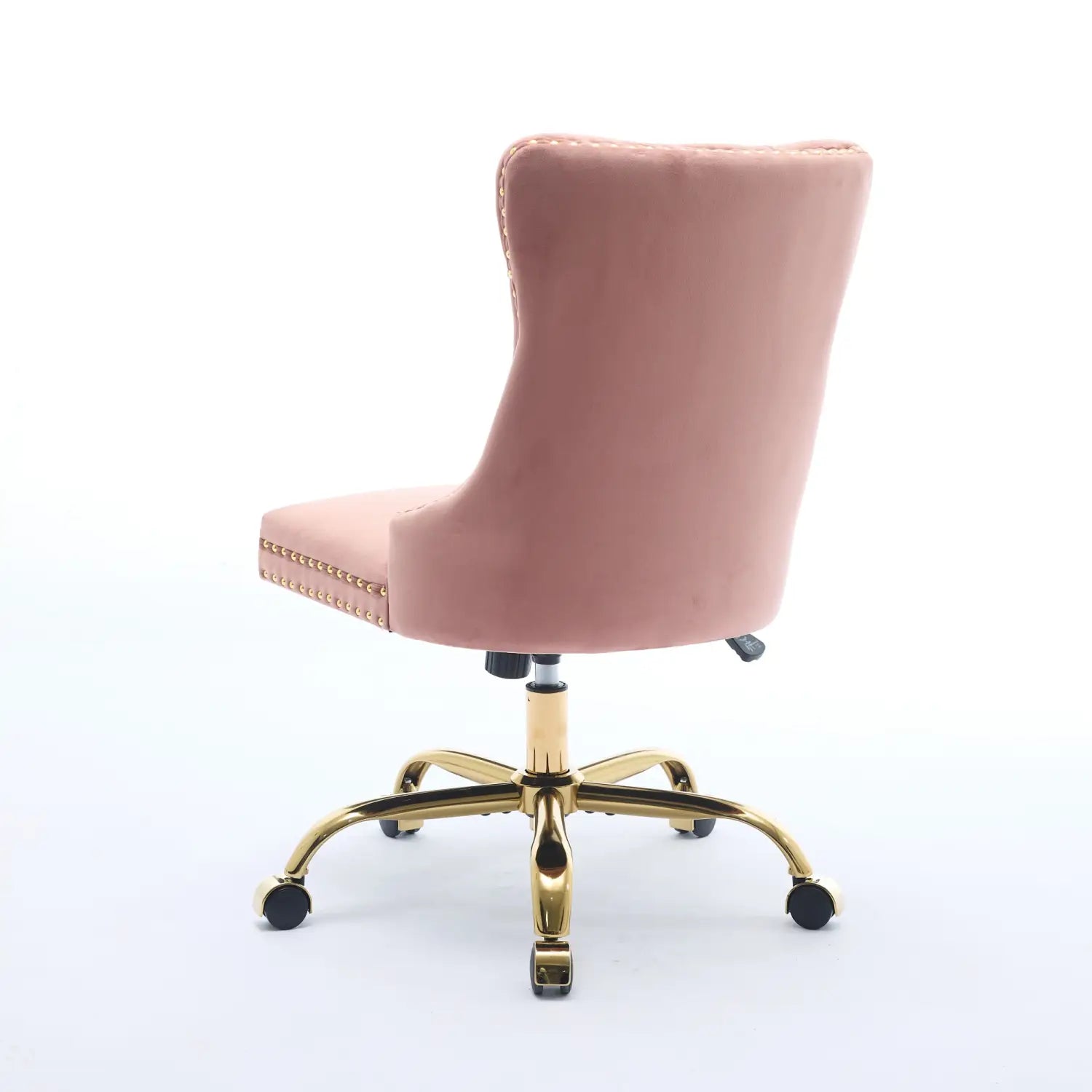 Un fauteuil de bureau rembourré en velours rose poudré, à capitonnage, avec une base en métal ton doré et une bordure à clous décoratifs.