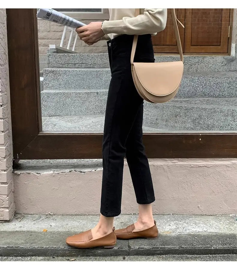 Tane Lederschlupflοafer mit minimalistischem Design und weich gerundeter Spitze, kombiniert mit schwarzen Samtgefütterten High-Waist-Jeans-Leggings.
