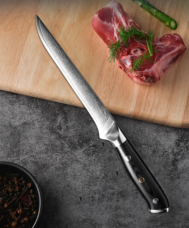 Ein elegantes Messerstück aus Damaststahl mit schwarzem, strukturiertem G10-Griff und silberner Parierstange ruht auf einer dunklen Arbeitsplatte neben rohem Fleisch, als Teil eines Damaststahl-Küchenmesserset 4-teilig mit G10-Griff.