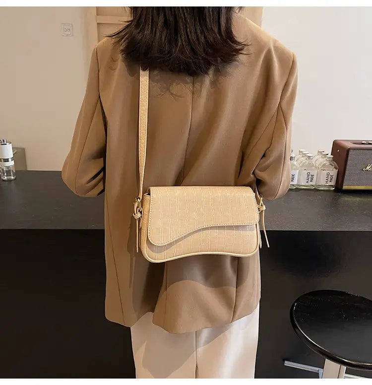 Beige leather messenger bag with crocodile texture and minimalist crossbody design ideal for everyday use.