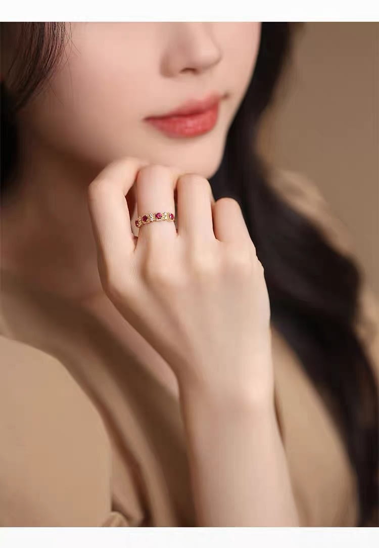 An 18k gold plated band ring featuring a delicate design with small pigeon blood ruby and diamond gemstones set in a subtle pattern.