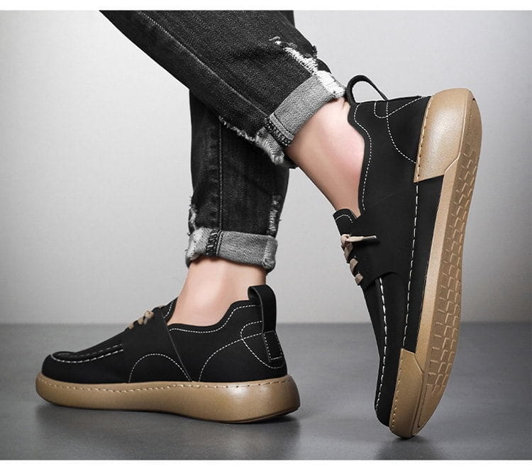 Chaussures en cuir style rétro britannique, élégance décontractée pour homme, noires en daim, style enfiler, semelles en caoutchouc marron, détails de couture blancs.