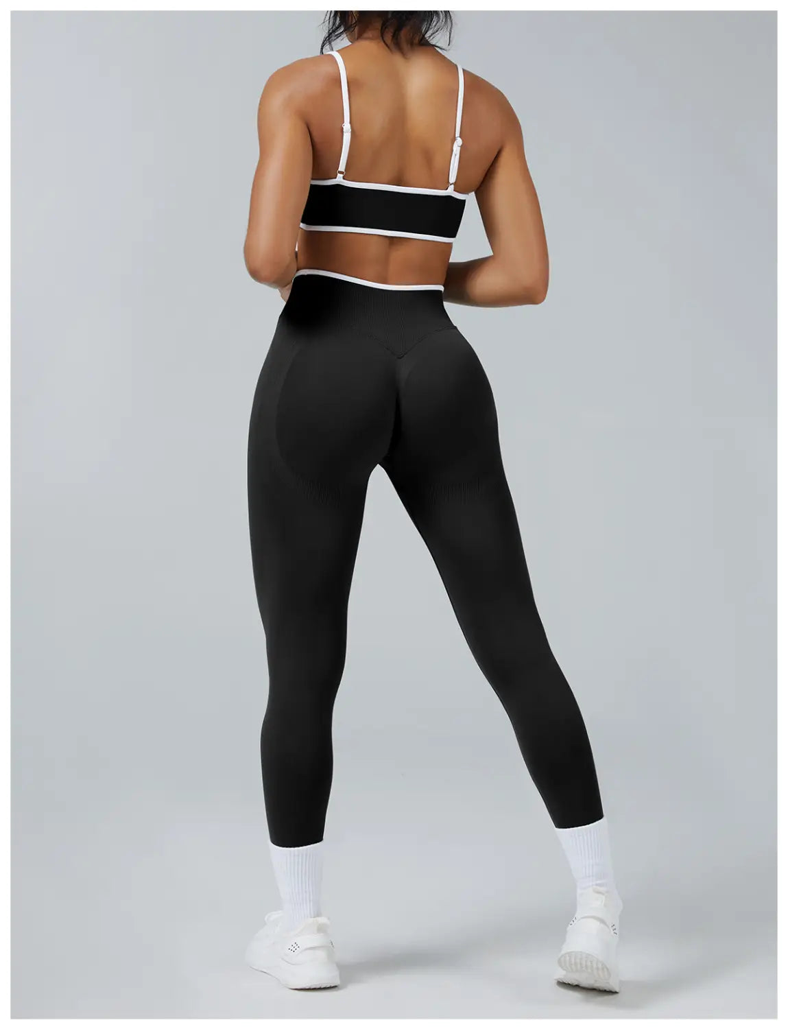 black seamless high waist sports yoga leggings with white trim at the waistband and straps shown from the back side