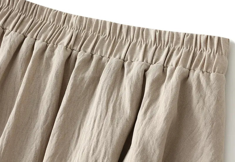beige linen trousers with an elastic waistband complement the pleated wide flare maxi skirt for a comfortable and stylish look.