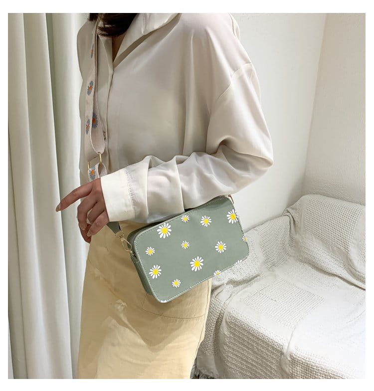 A light green pu leather daisy flower crossbody bag with a chain strap featuring a pattern of white daisies with yellow centers.