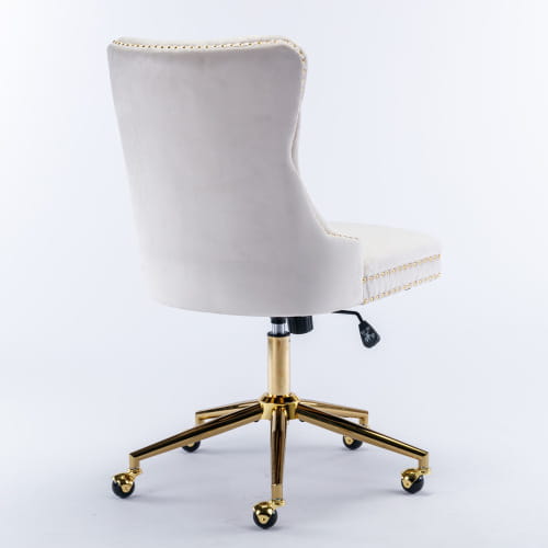 Silla de oficina de terciopelo color crema con botones tipo capitoné, marco metálico de tono dorado y remate con tachuelas, diseñada para un espacio de trabajo elegante.