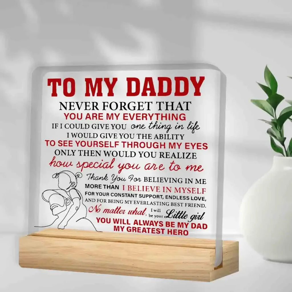 White rectangular acrylic desk sign with red and black text and a girl hugging an adult on light wood stand for daddy gift