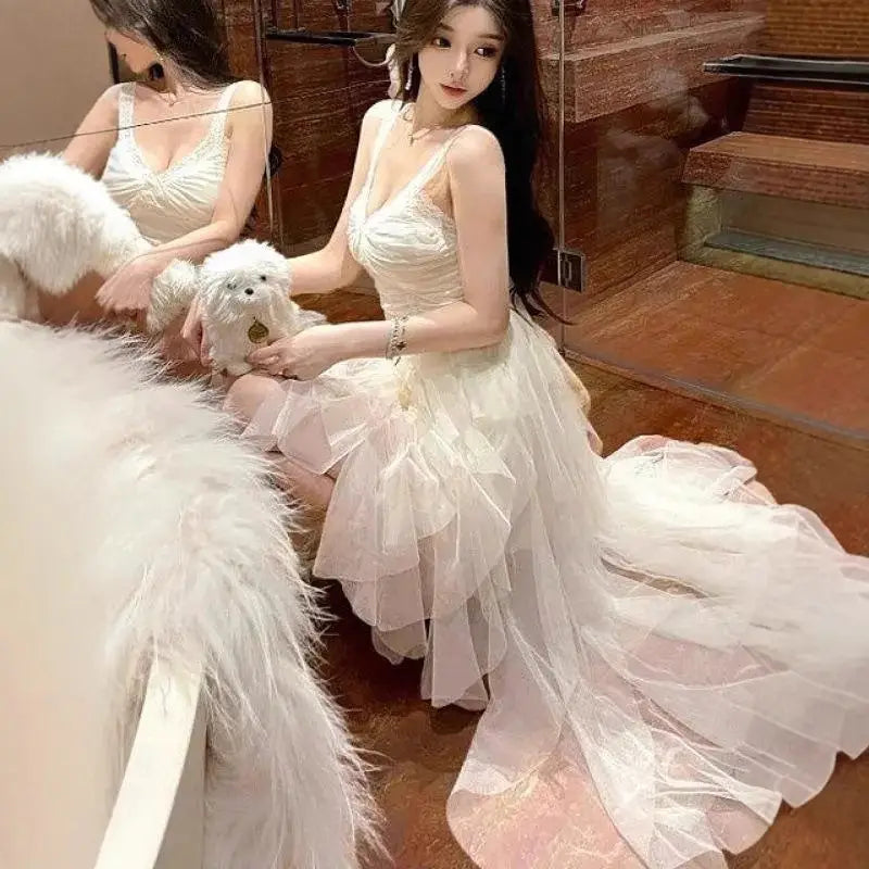 A flowing off-white tiered tulle and lace mesh evening gown with delicate lace detailing and a plunging neckline.