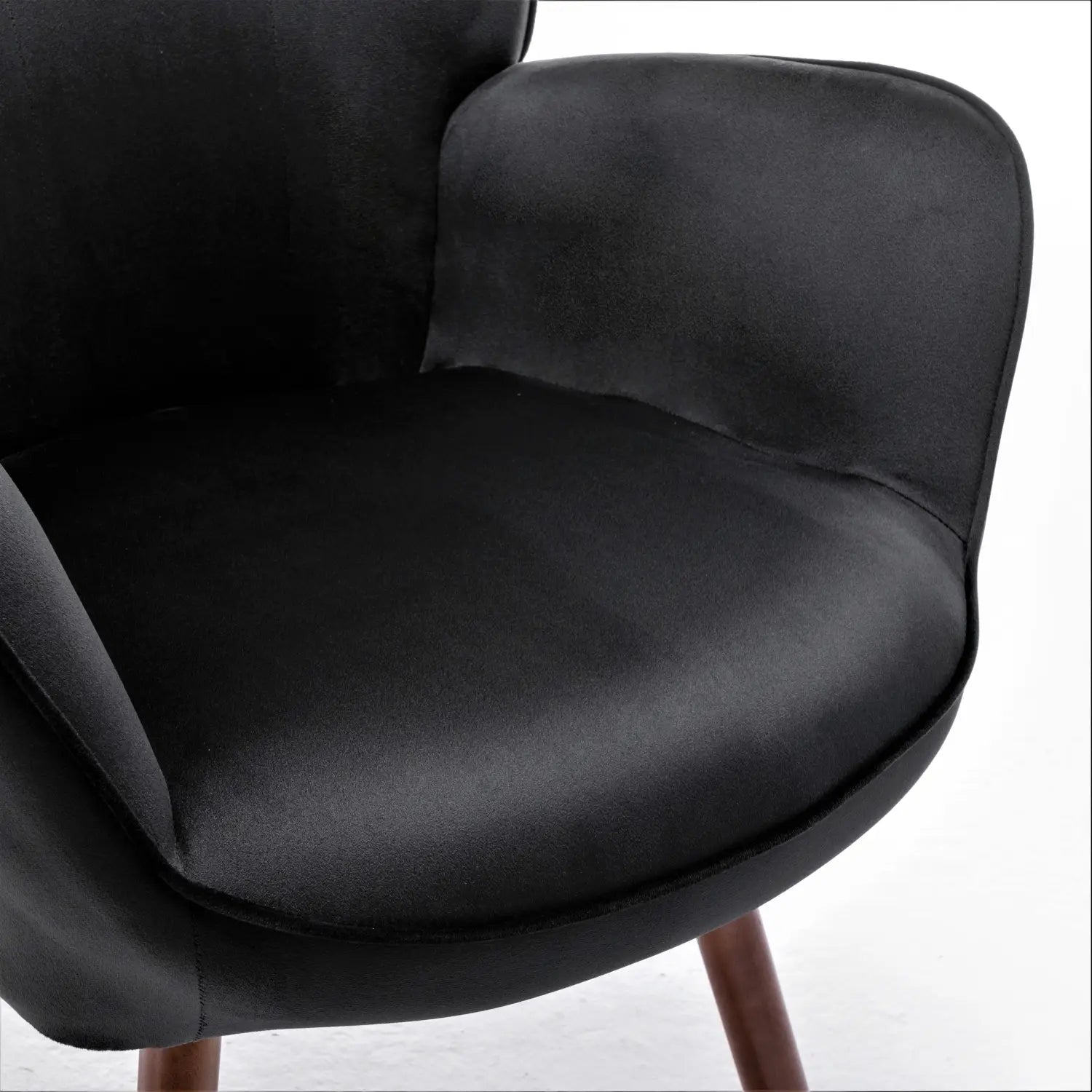 Silla de acento tipo wingback con terciopelo negro acolchado y con botones, con patas de madera, tapizada en una tela de terciopelo suave para una colocación elegante.
