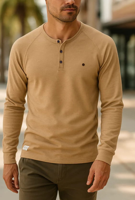 Chemise henley à manches longues côtelée pour homme, de couleur beige, avec des boutons foncés et un petit point noir sur la poitrine.