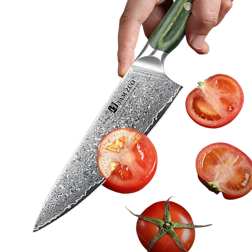 A damascus steel chef knife with a green and black patterned handle held over sliced tomatoes on a wooden board