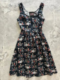 A black sleeveless fit and flare dress by dapper fox featuring a vibrant retro print of cyclists and vintage street scenes
