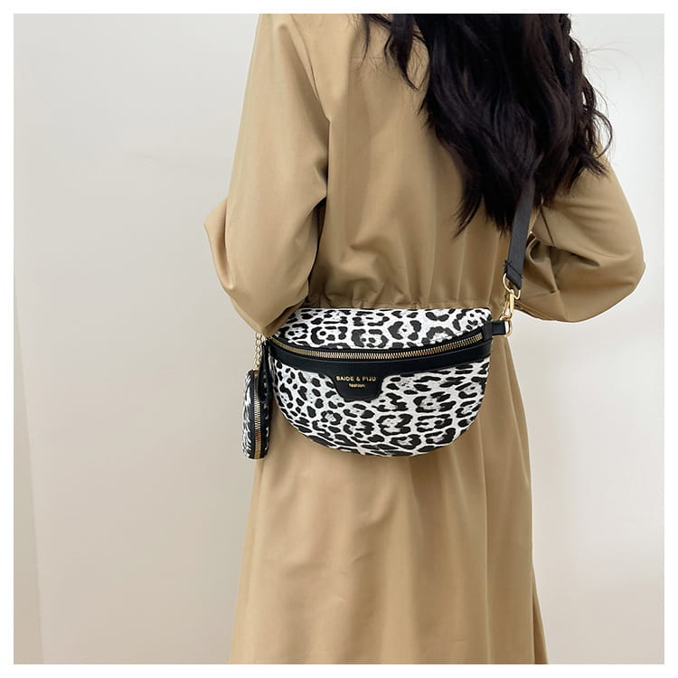 Sac banane à imprimé léopard noir et blanc avec fermeture éclair, bordure en cuir, quincaillerie ton or et petite pochette à monnaie assortie attachée.