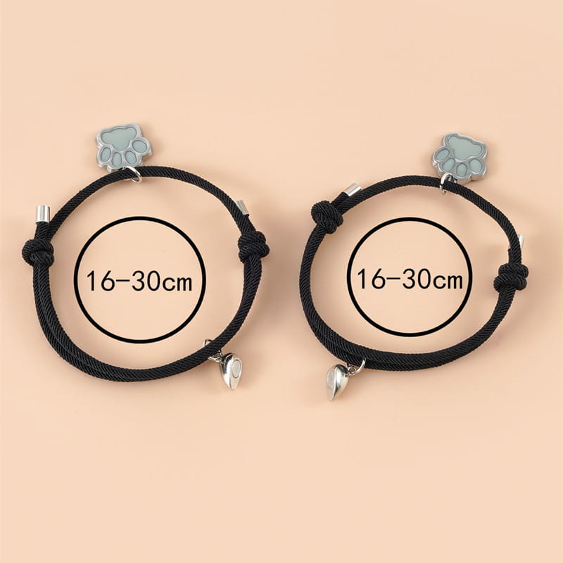 Black corded luminous magnetic heart paw print couple bracelets featuring light gray paw print charms and silver heart pendants.