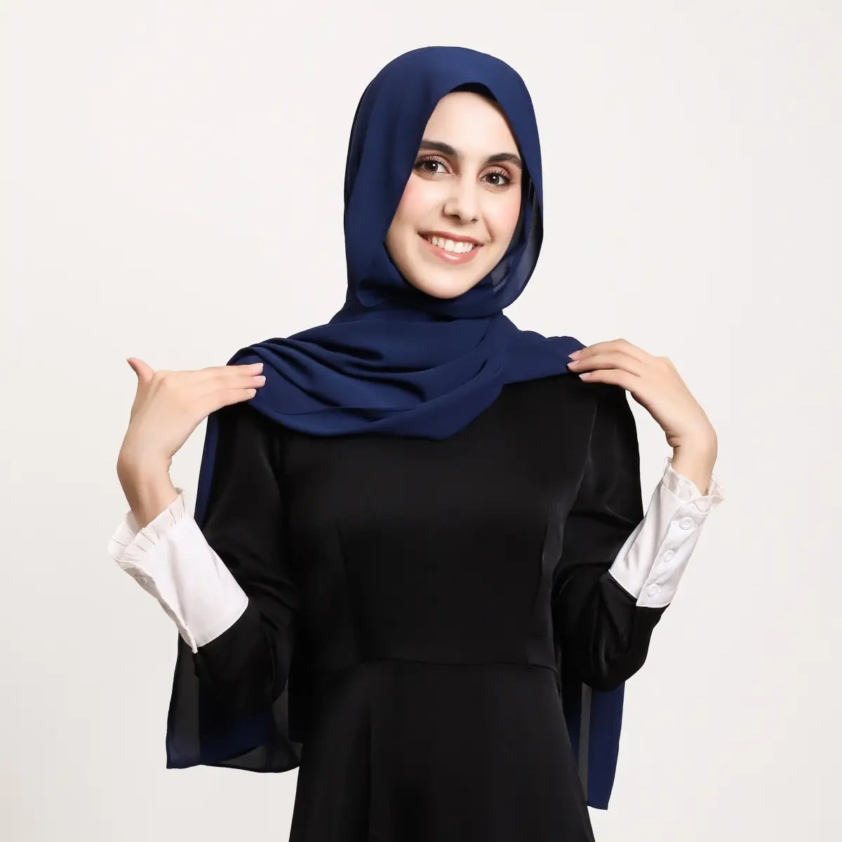 Un hijab magnétique en mousseline bleu marine, dont le tissu fluide s’écoule avec élégance sur la tête et les épaules de la personne qui le porte.